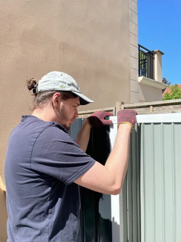 Un membre de l'équipe Sakura Home fixe un panneau de clôture chez un client