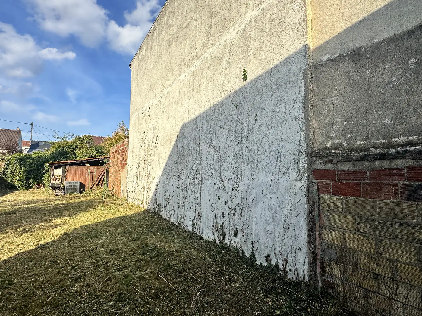 Mur débarrassé du lierre et pied de mur dégagé après un débroussaillage par Sakura Home
