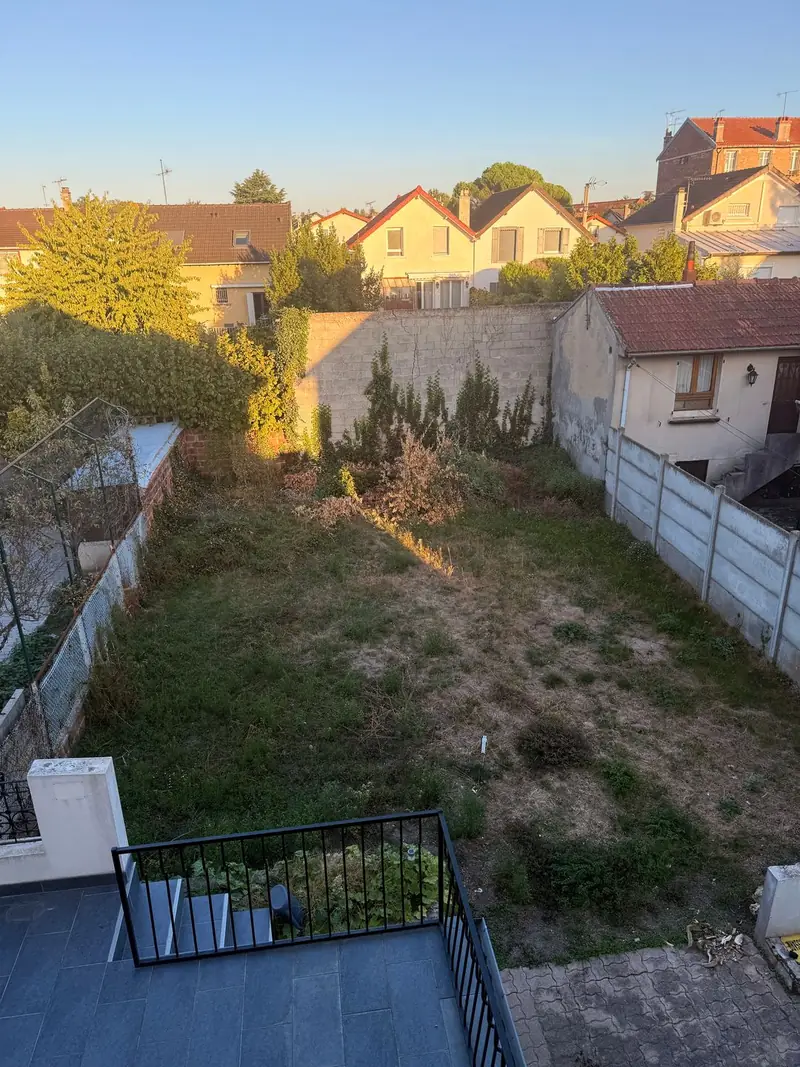 Photo réelle du jardin du client avant le projet : pelouse sèche, massifs envahis, mur au fond